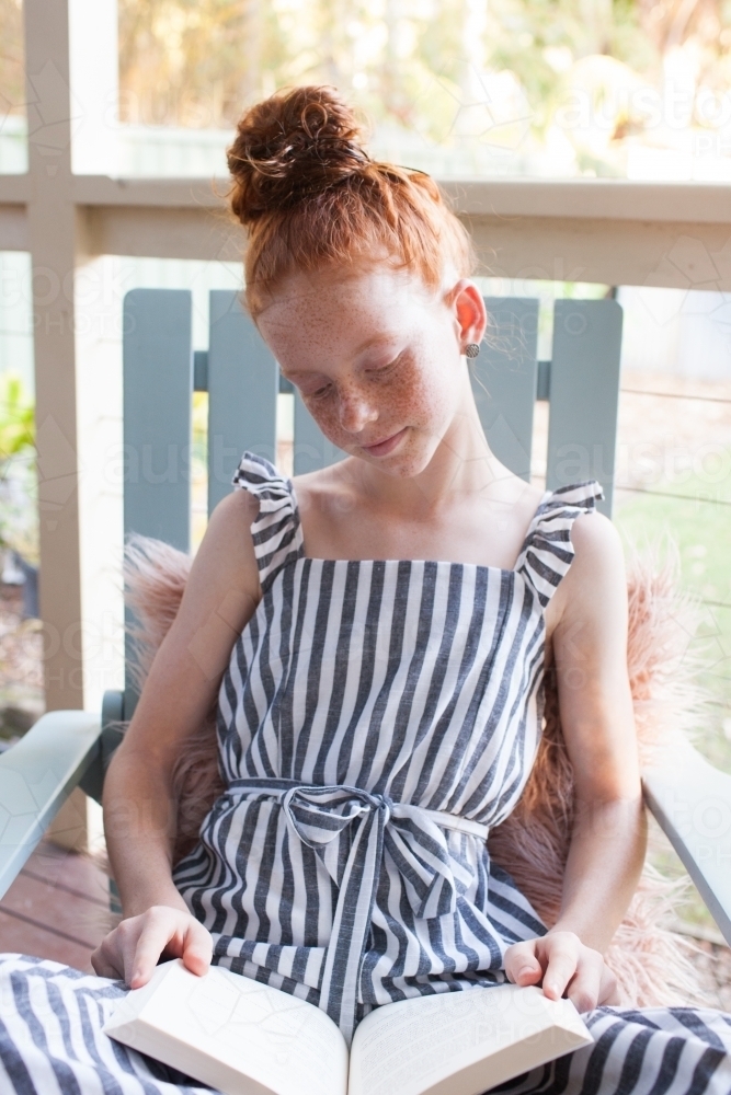 Girl reading a book on a verandah - Australian Stock Image