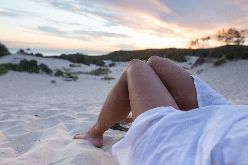 Girl relaxing at the beach watching the sunset - Australian Stock Image