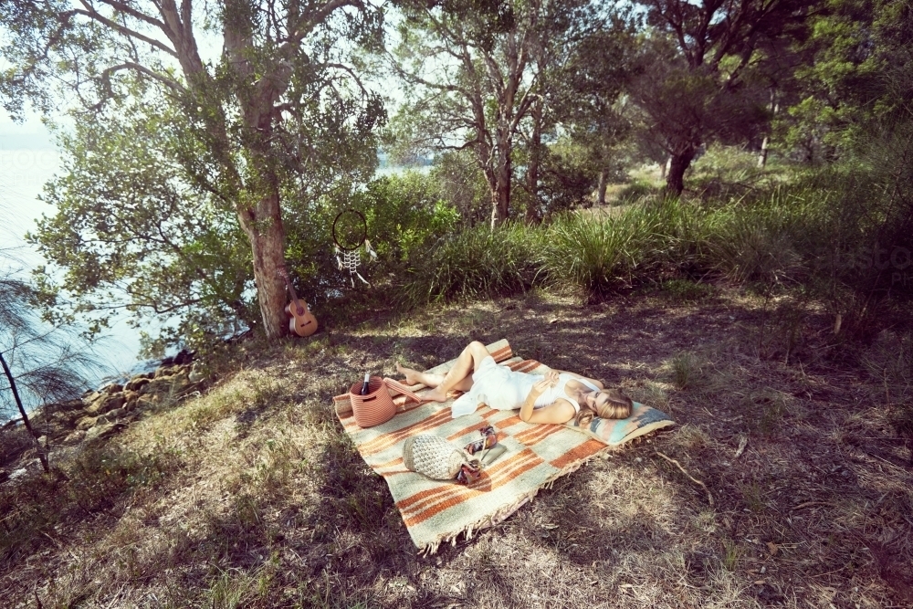 Girl resting on a picnic mat in the woods - Australian Stock Image