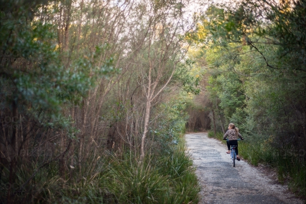 Girl riding bike along path in bush - Australian Stock Image
