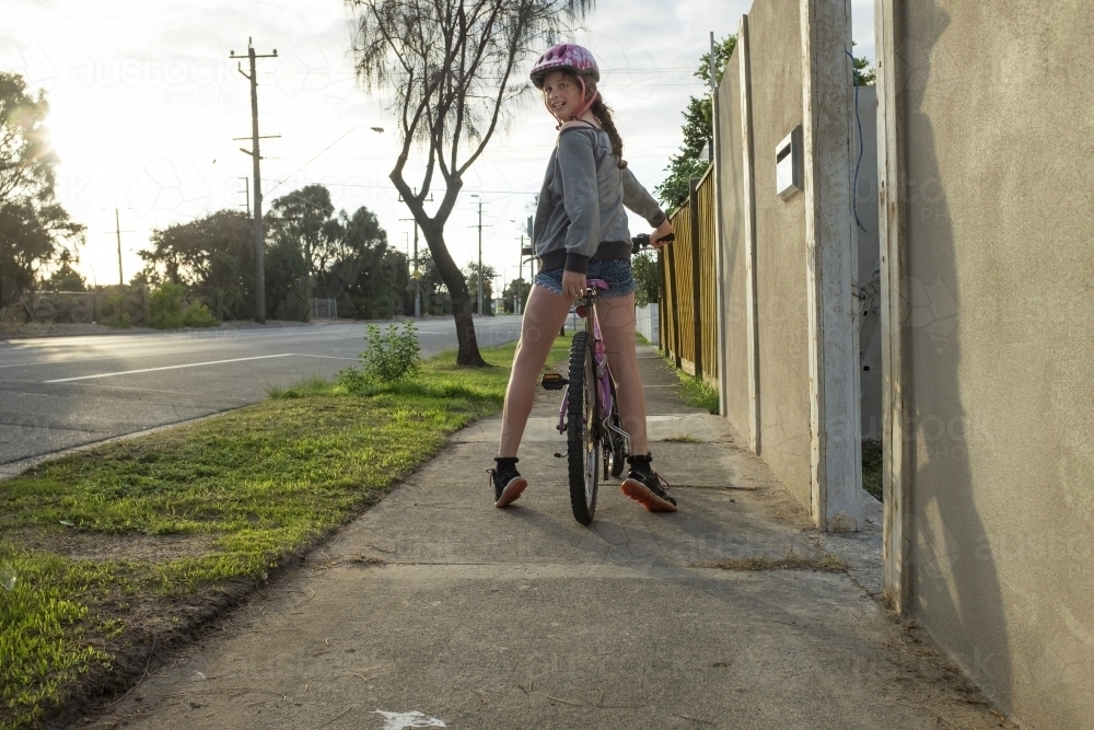 Girl riding bike along urban street - Australian Stock Image