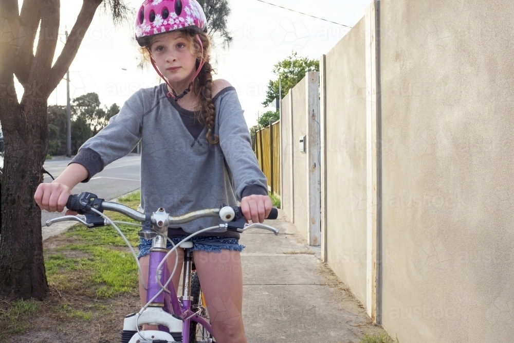 Girl riding bike along urban street. - Australian Stock Image