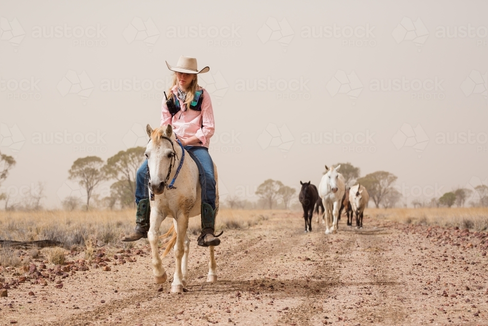 Girl Riding Pony on a dirt track - Australian Stock Image