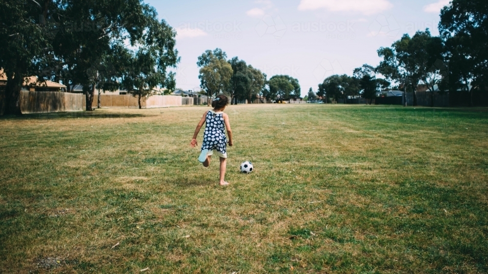 Girl running after a soccer ball - Australian Stock Image