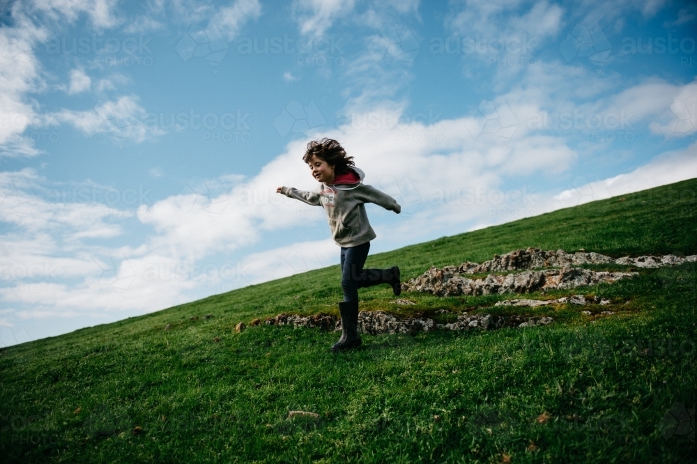 Girl running down a grassy hill - Australian Stock Image