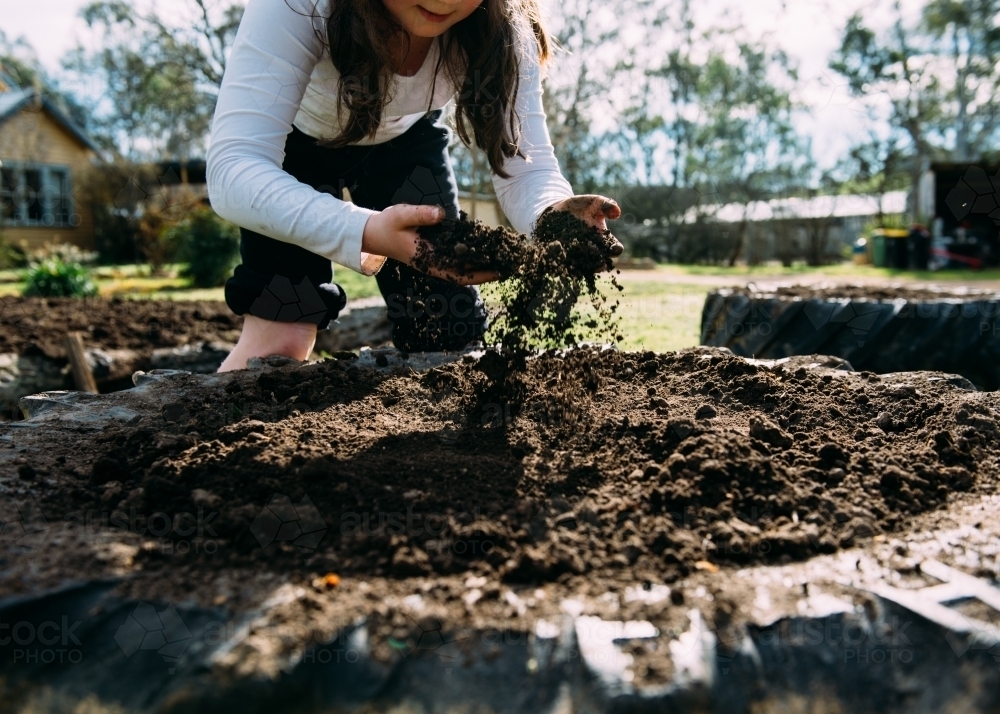 Girl running soil through fingers - Australian Stock Image