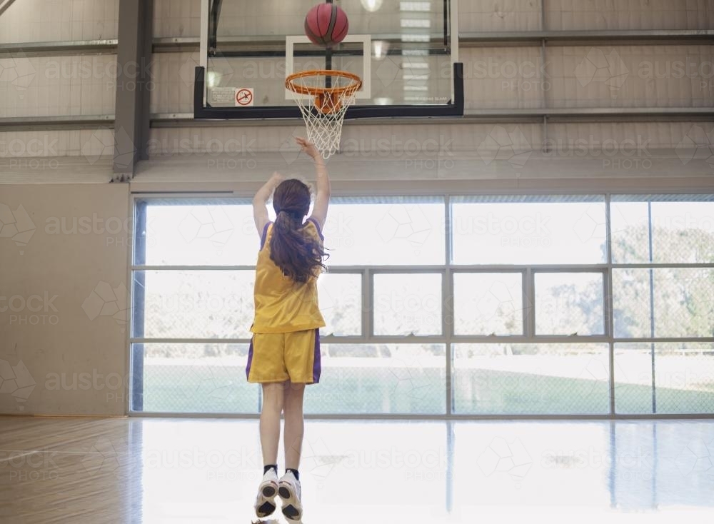 girl shooting basketball hoop. - Australian Stock Image
