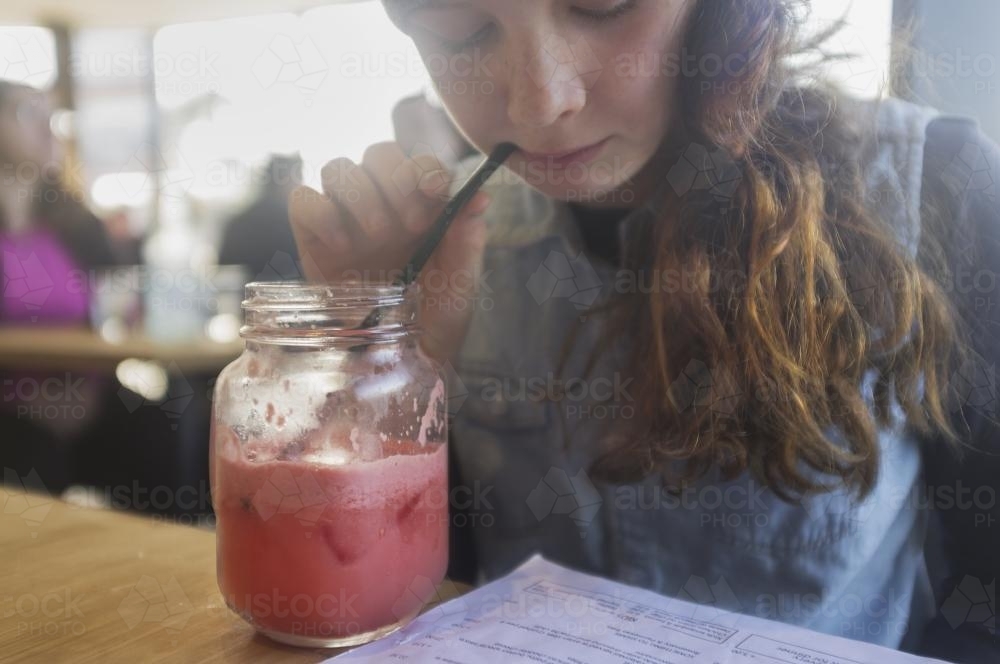 Girl sips watermelon juice in cafe - Australian Stock Image