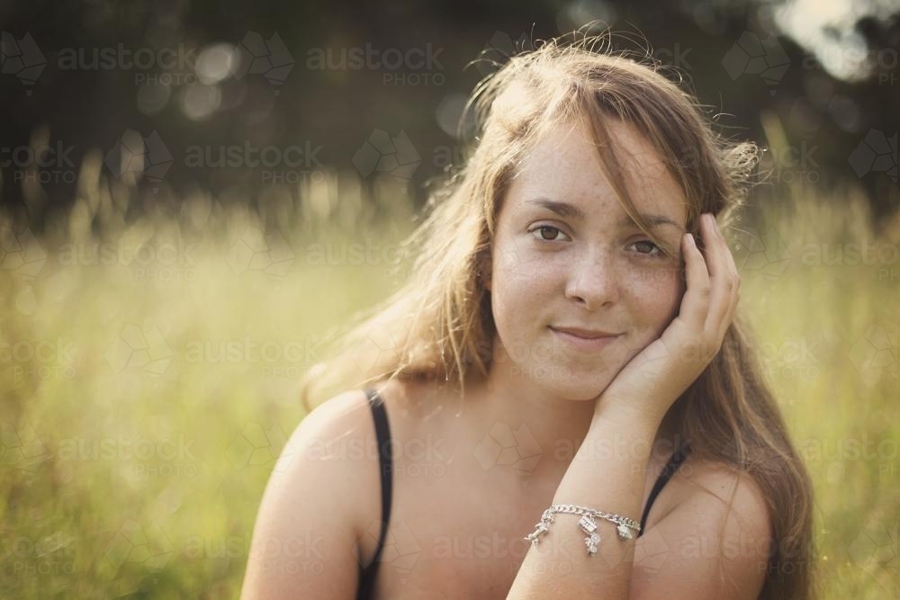 Girl sitting in long grass - Australian Stock Image