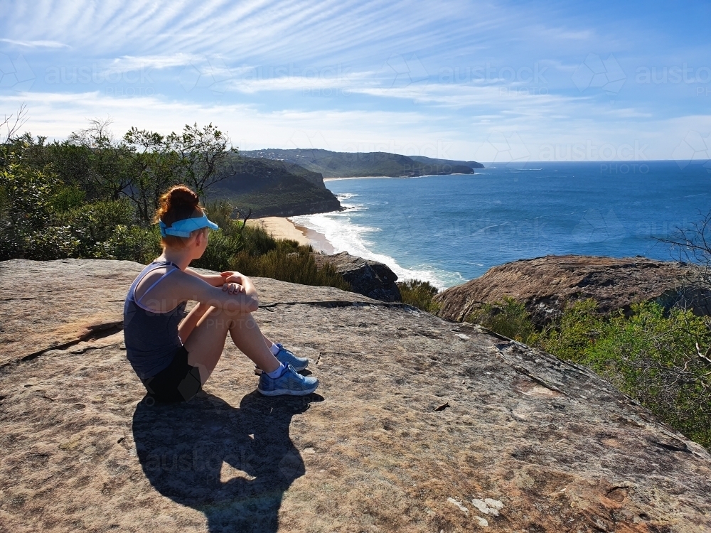 Image of Girl sitting on a rock looking at the view of a beach ...