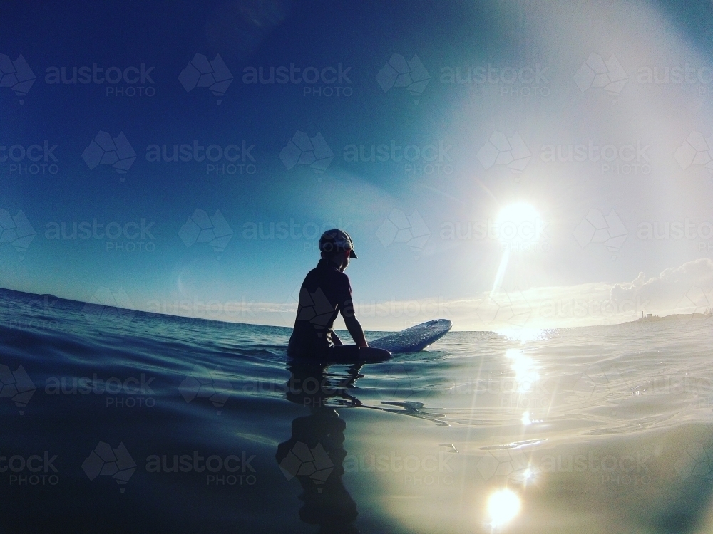 Girl sitting on a surfboard at the beach - Australian Stock Image