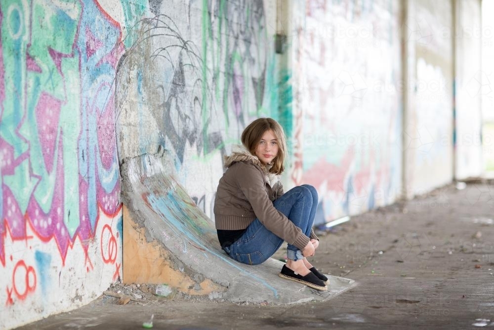 Girl sitting on ramp with graffiti - Australian Stock Image