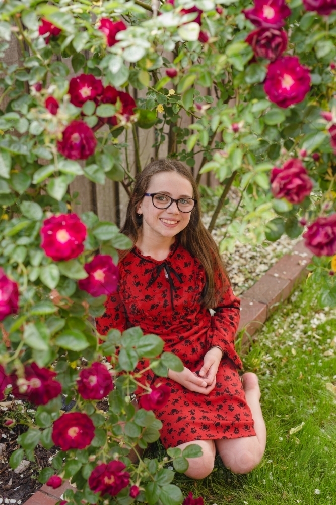 Girl sitting under a rose bush - Australian Stock Image