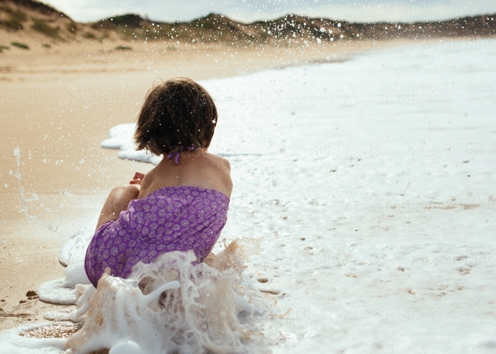 Girl splashing waves as they roll in - Australian Stock Image