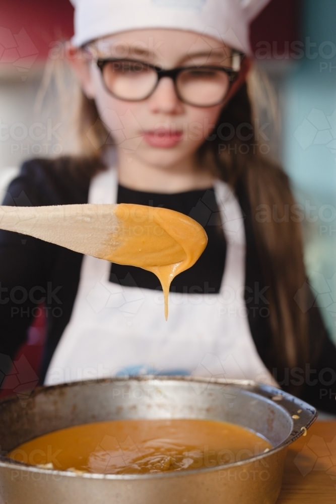 Girl spooning cake mixture into tin - Australian Stock Image