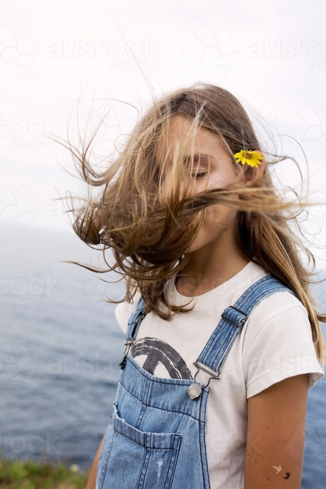 Girl standing by the ocean with hair flying in her face - Australian Stock Image