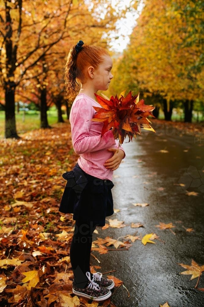 Girl standing in a street of autumn trees - Australian Stock Image