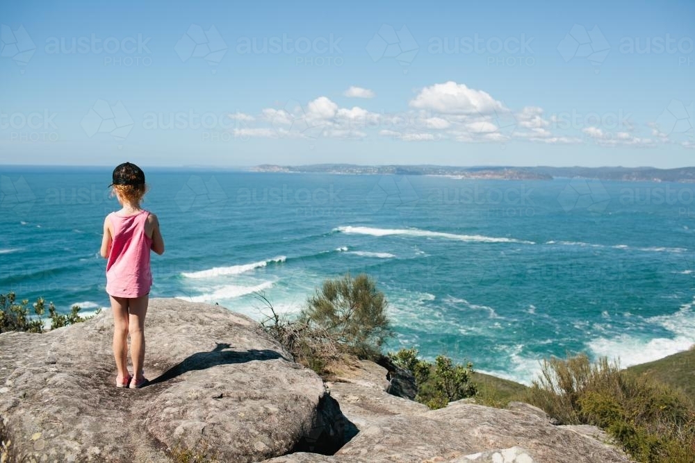 Girl standing on a rock platform looking at the view - Australian Stock Image