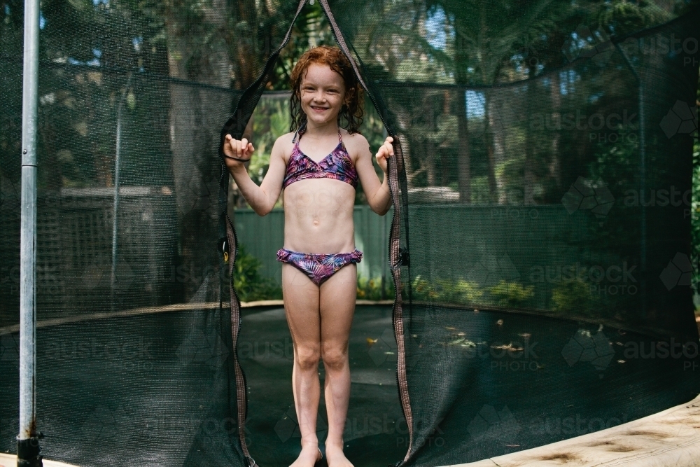 Girl standing on a trampoline in a bikini - Australian Stock Image