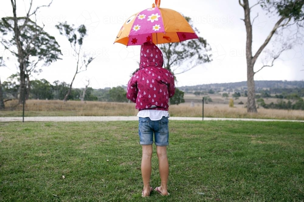 Girl standing outside in the rain holding umbrella - Australian Stock Image