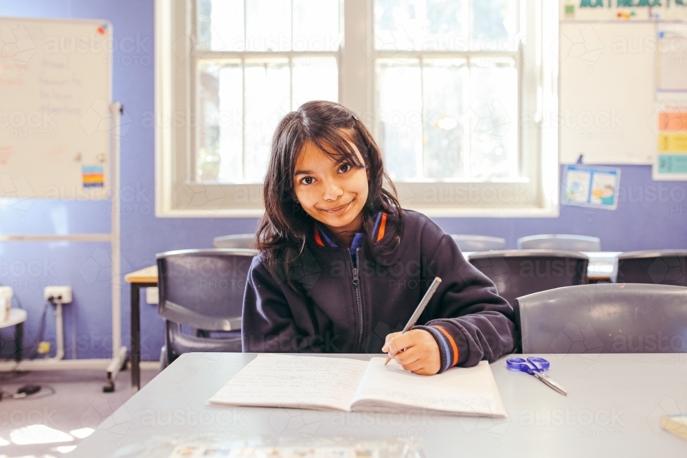Image of Girl student sitting at her desk in a classroom doing her ...