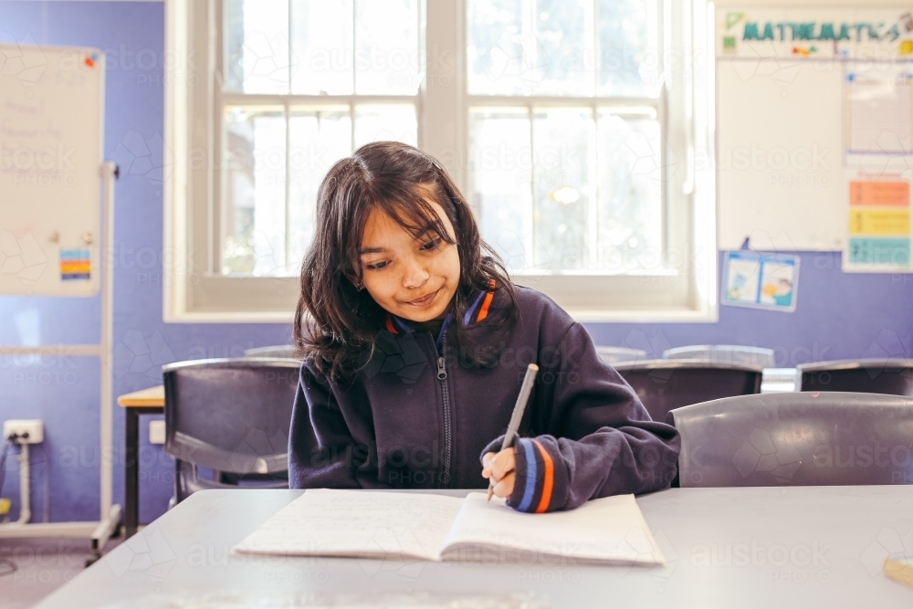 Image of Girl student sitting at her desk in a classroom doing her ...