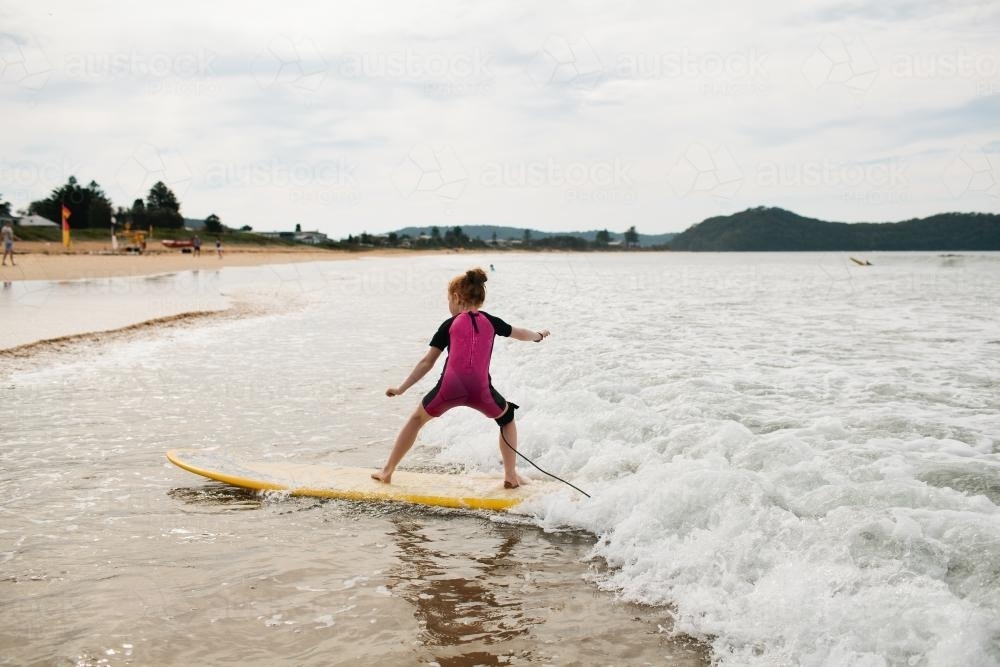 Girl surfing at the beach - Australian Stock Image