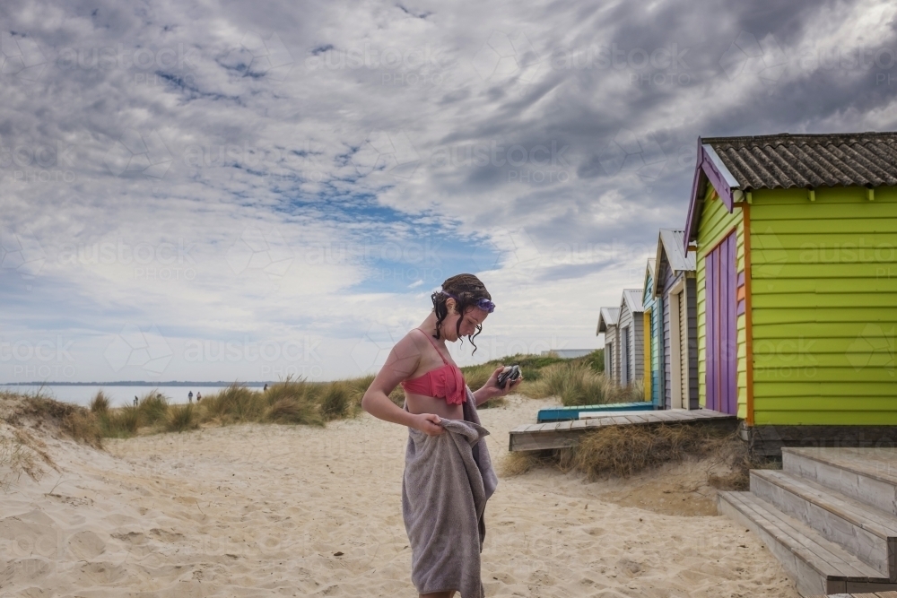 Girl swimming at beach with colourful beach boxes - Australian Stock Image