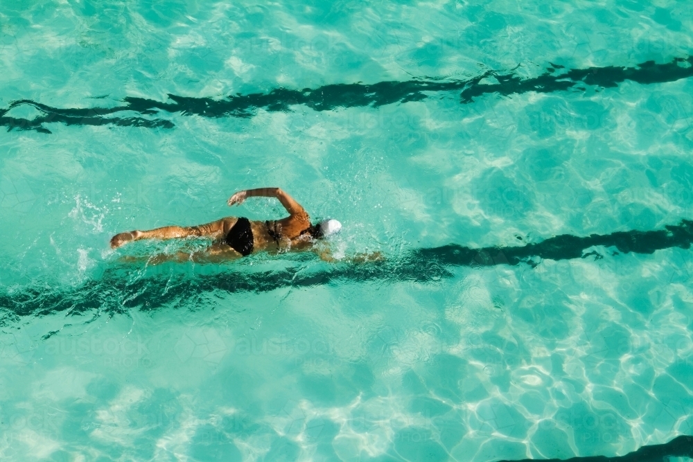Girl swimming laps in a pool overhead view - Australian Stock Image