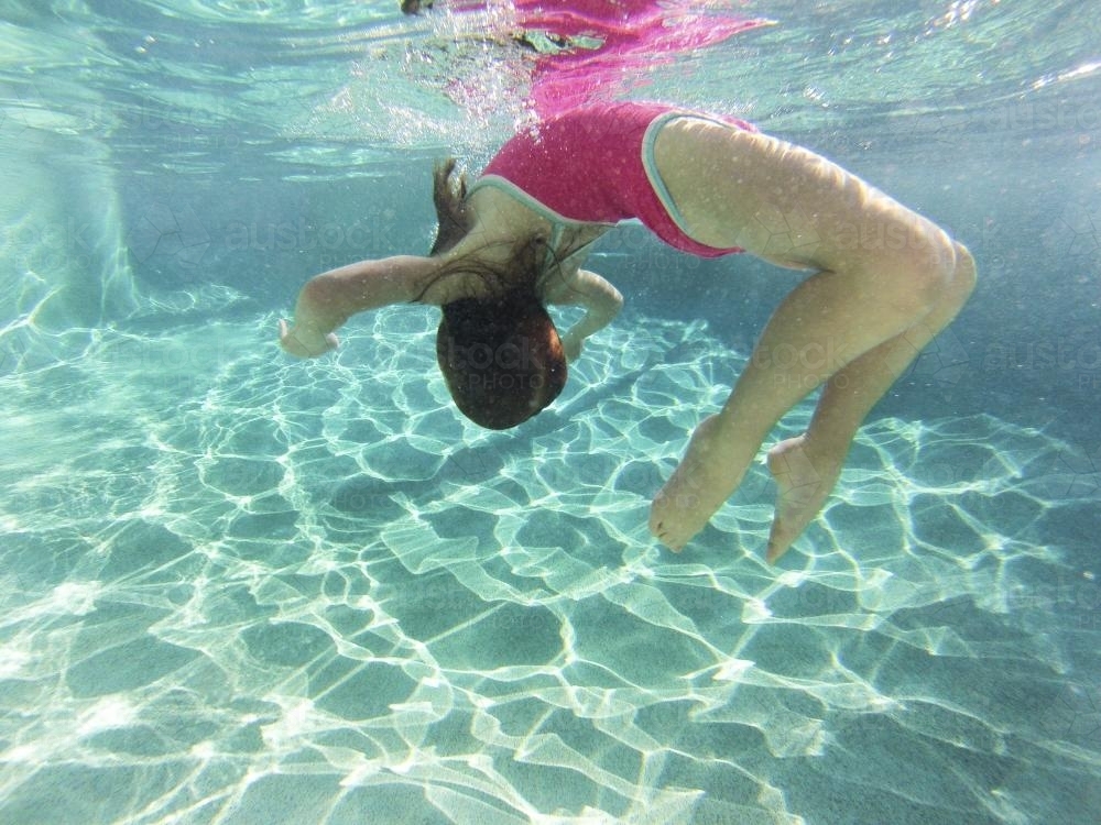 Girl swimming underwater in a pool - Australian Stock Image