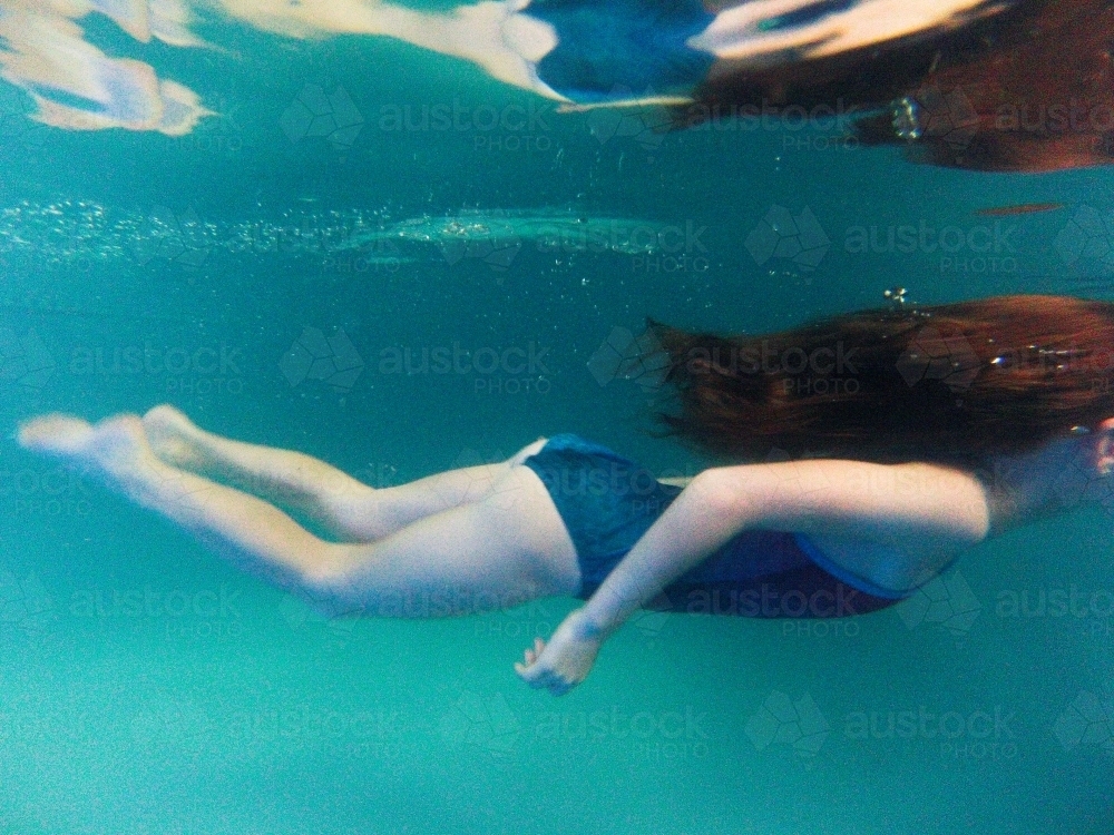 Girl swimming underwater in a pool - Australian Stock Image