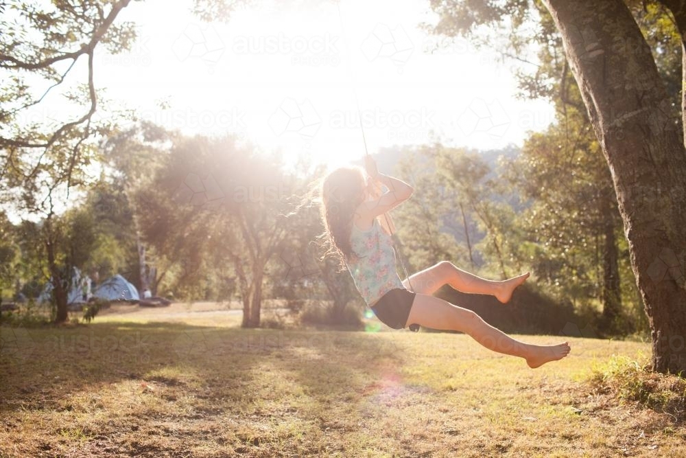 Girl swinging on a rope swing at a campsite - Australian Stock Image