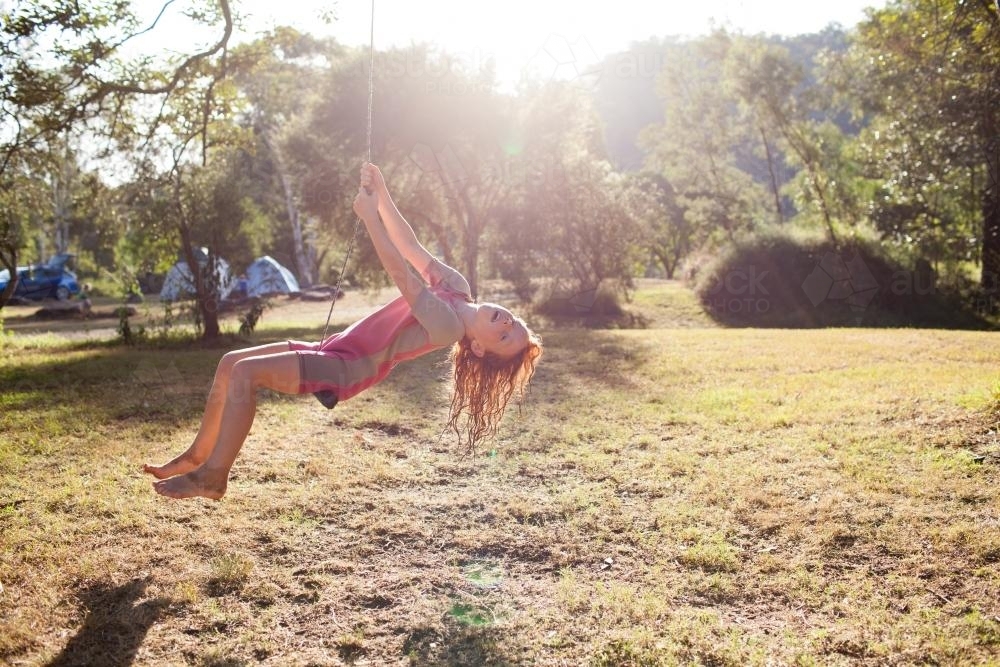 Girl swinging on a rope swing at a campsite - Australian Stock Image