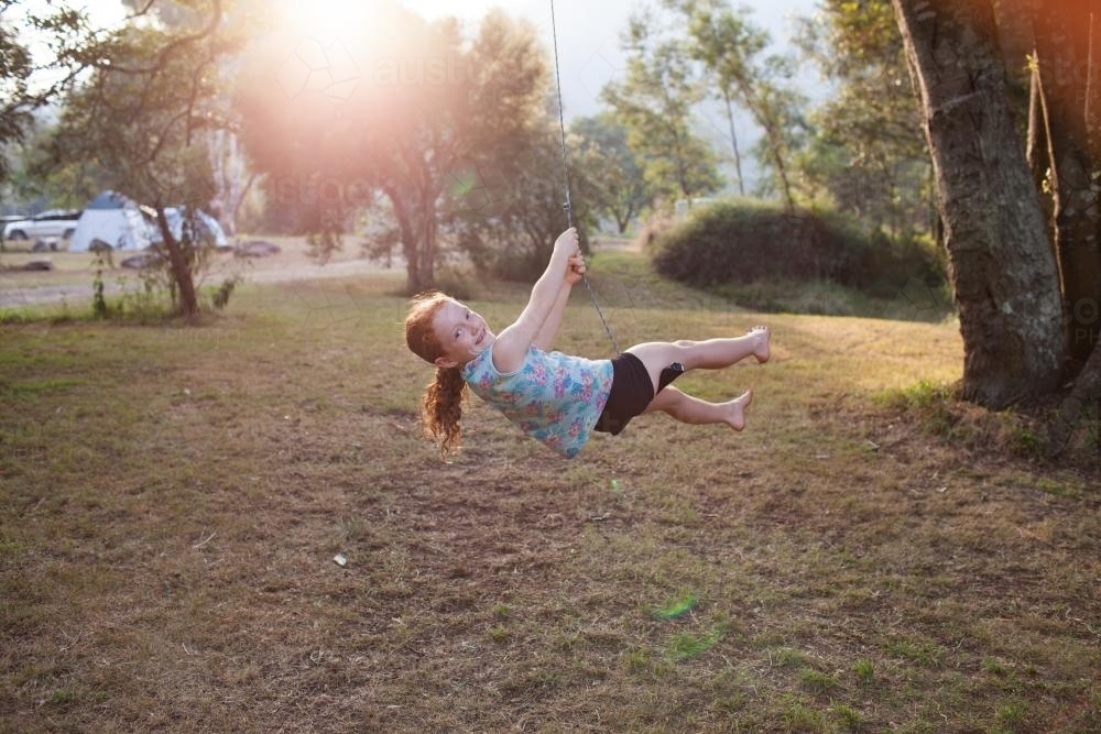 Girl swinging on a rope swing - Australian Stock Image