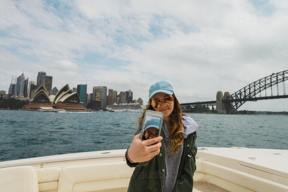 girl taking selfie on Sydney Harbour, with bridge and opera house - Australian Stock Image