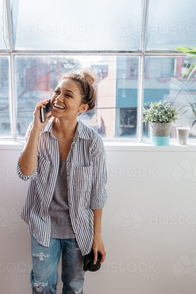 Girl talking on her phone against an office window - Australian Stock Image