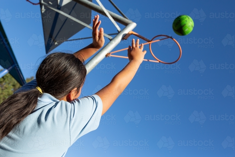 Girl throwing ball through goal hoop - Australian Stock Image