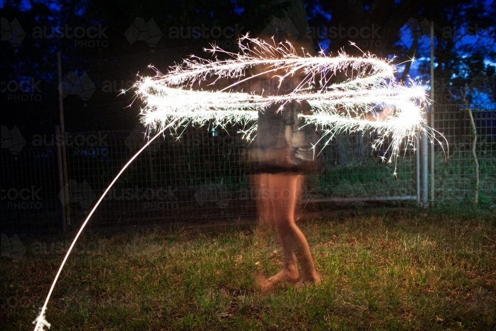 Girl twirling a sparkler at night - Australian Stock Image