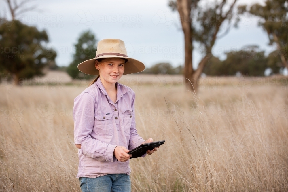 Girl using an ipad in the paddock on a farm - Australian Stock Image