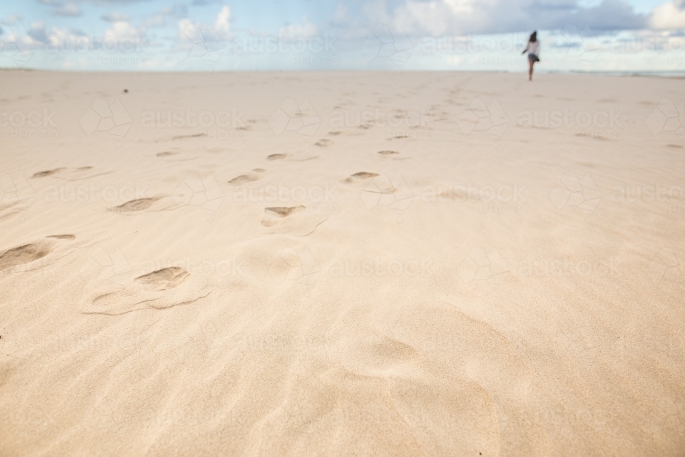 Girl walking alone on a beach - Australian Stock Image