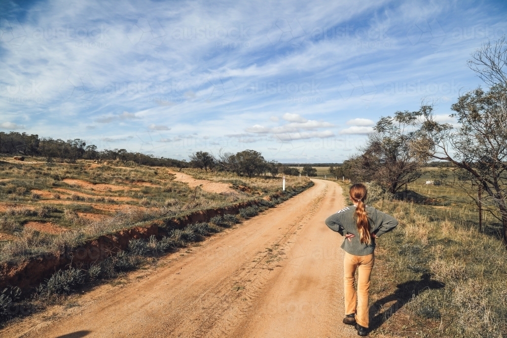 Girl walking along dirt track in rural Australian landscape - Australian Stock Image