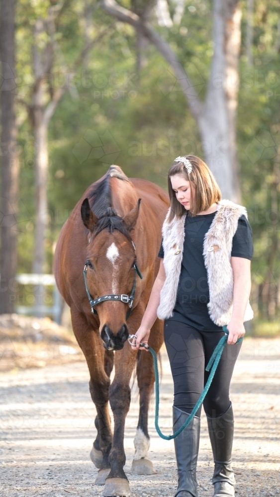 Girl walking along holding horses lead rope - Australian Stock Image