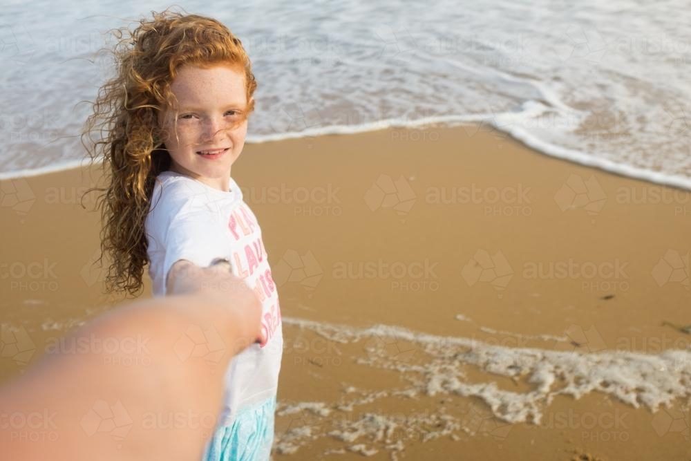 Girl walking along the beach holding hands - Australian Stock Image
