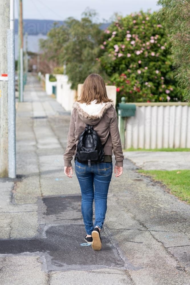Girl walking away down deserted footpath - Australian Stock Image
