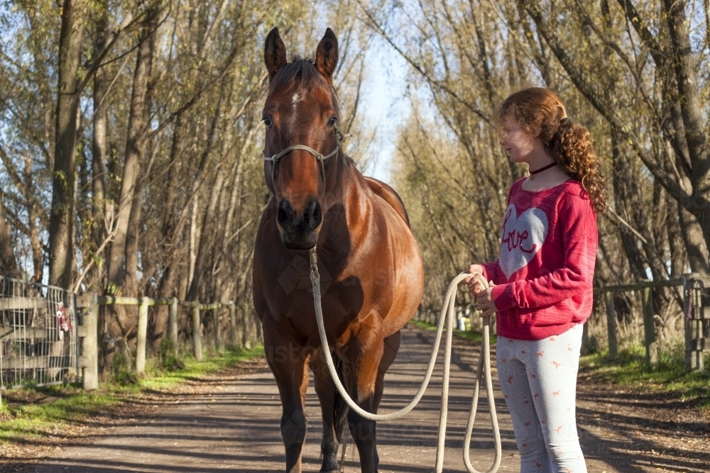 Girl walking her horse in scenic background - Australian Stock Image