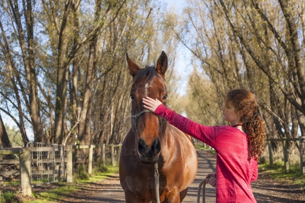 Girl walking her horse in scenic background - Australian Stock Image