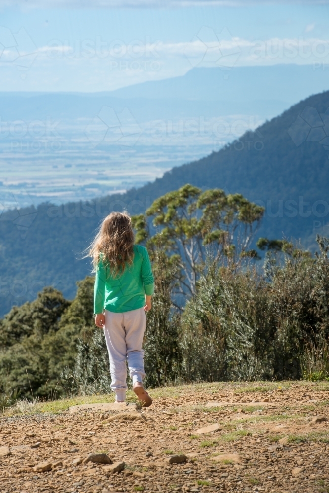 Girl walking on mountain overlooking mountains - Australian Stock Image