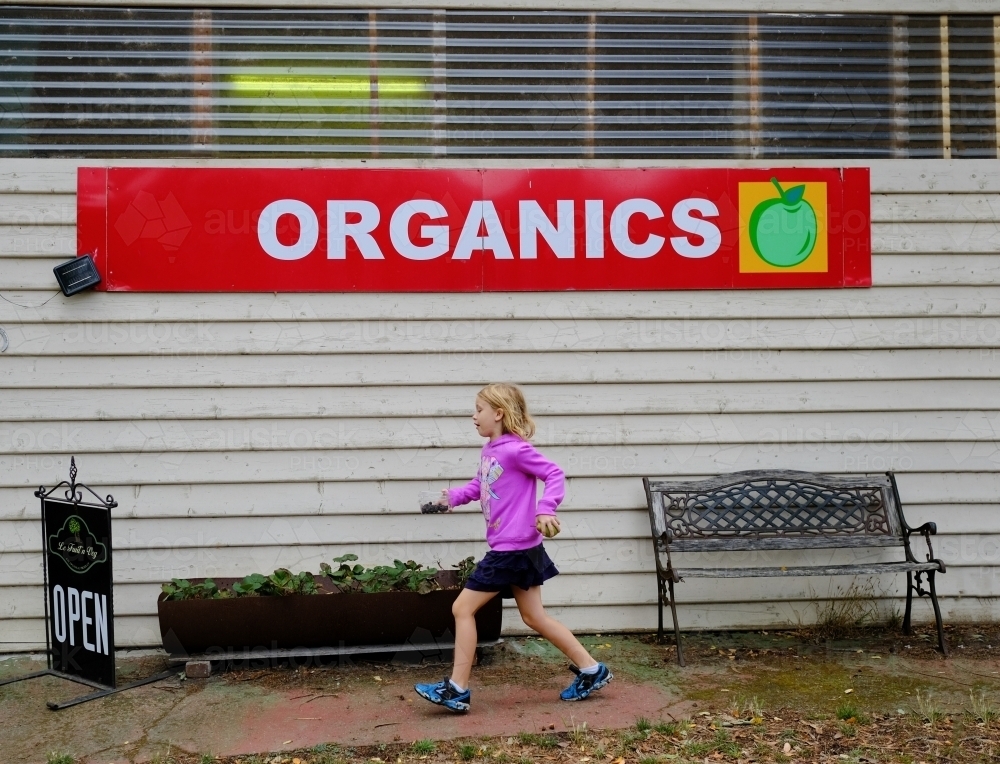 Girl walking past organic fruit farm shop - Australian Stock Image