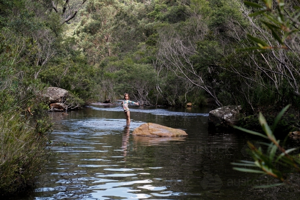 Girl wearing a swimsuit exploring a river by herself - Australian Stock Image