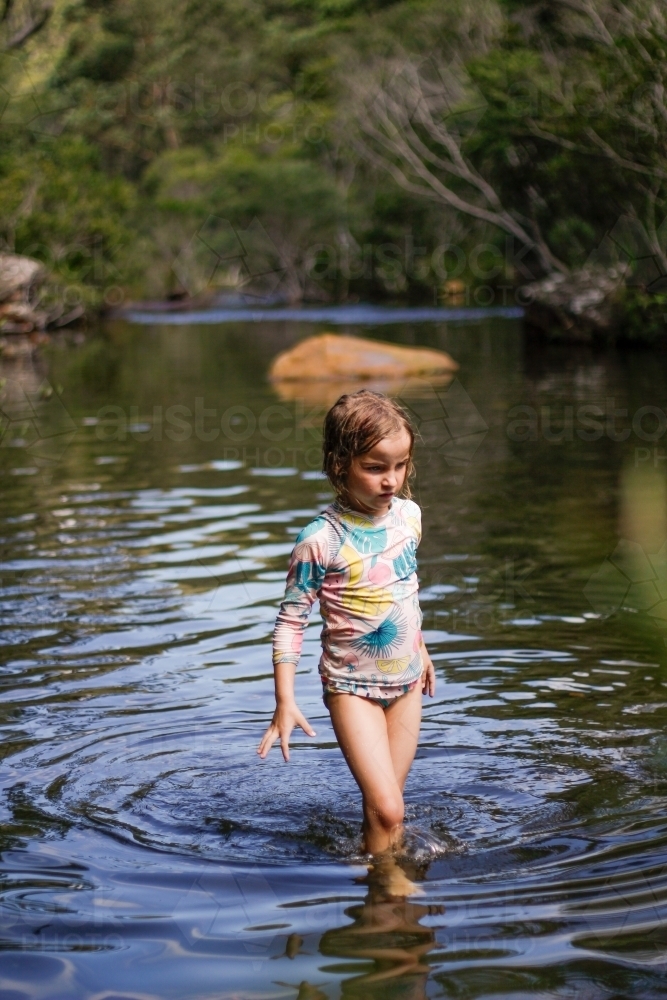 Girl wearing a swimsuit exploring a river by herself - Australian Stock Image